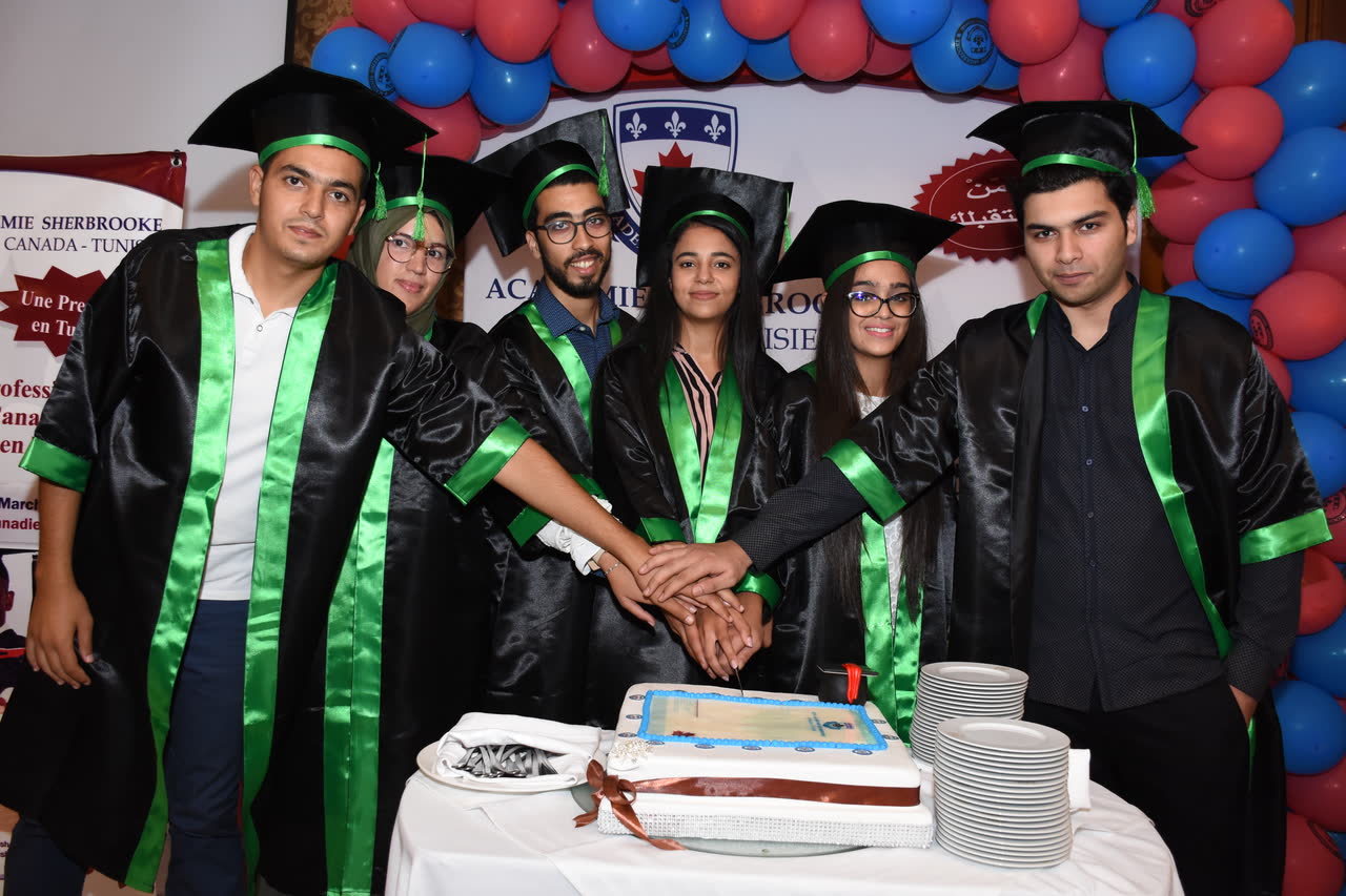 Quatre diplômés découpent ensemble le gâteau de la promotion
