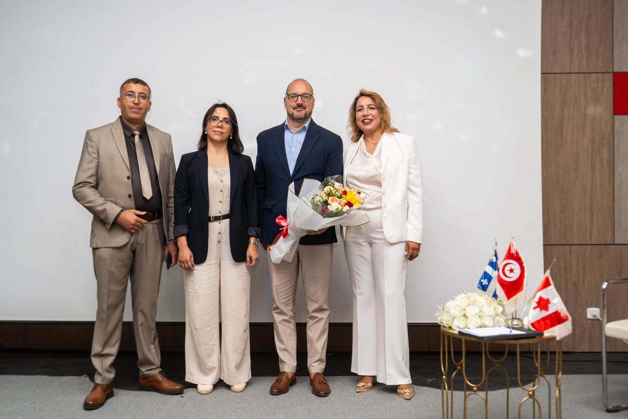 Quatre personnes posant ensemble, drapeaux tunisien et canadien à côté d'elles