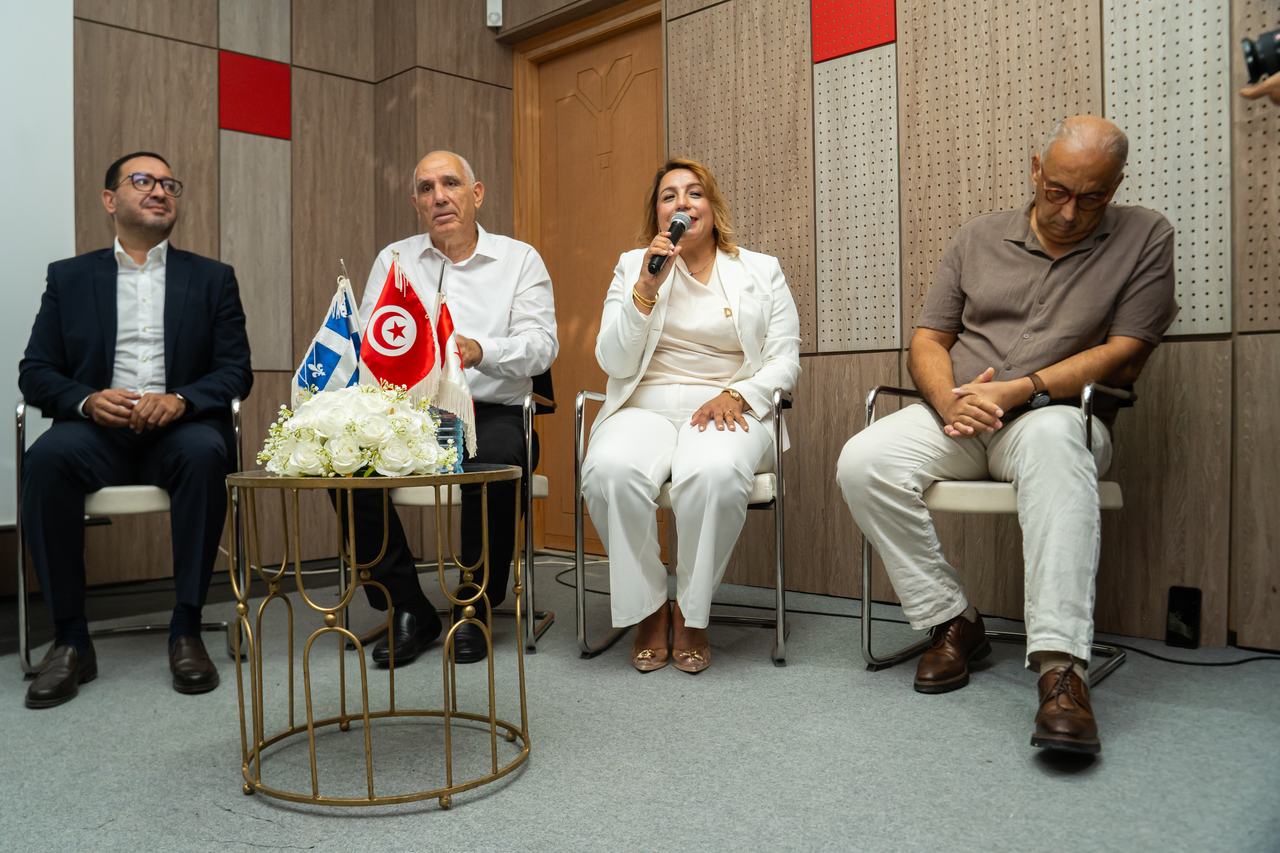 Un panel d'intervenants, drapeaux tunisien et canadien au centre